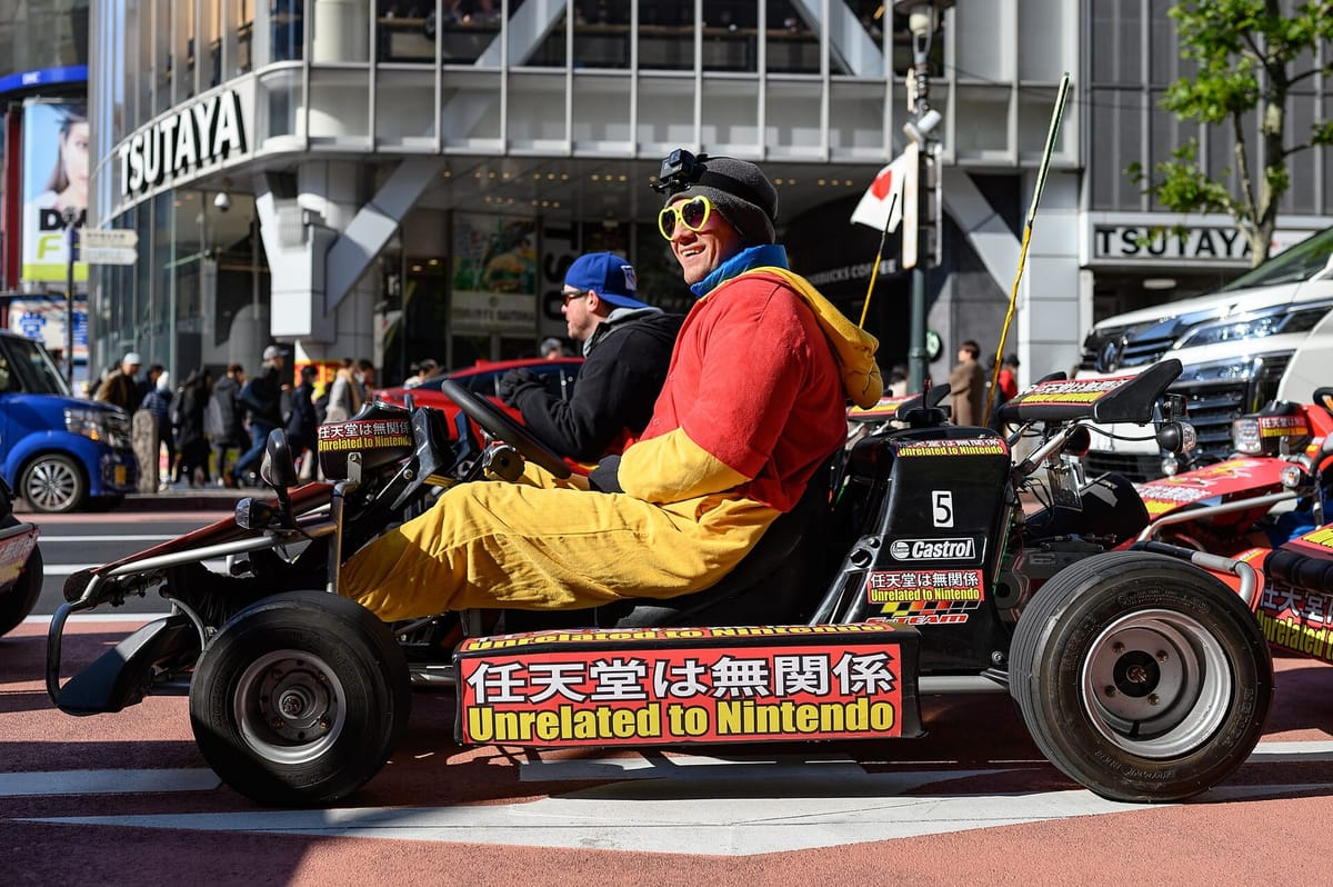 A line of street karts with costumed drivers waiting at a Tokyo traffic light